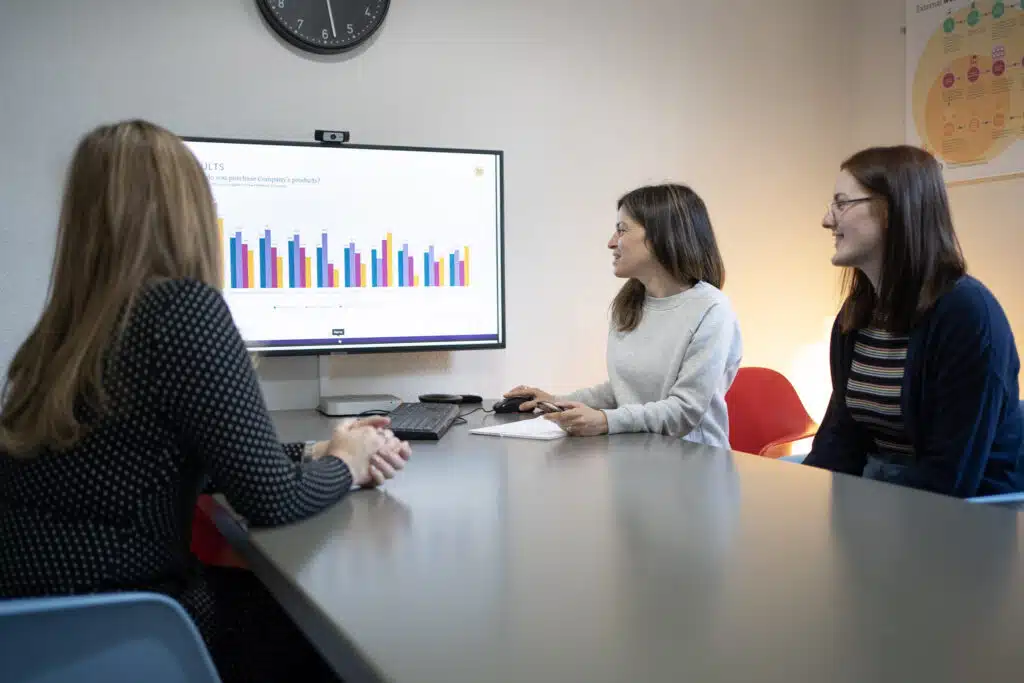 A photo of three researchers looking at a column chart on a screen